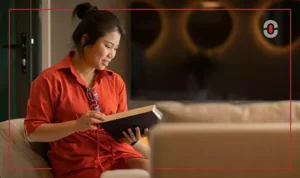 A young woman in a red outfit sits comfortably in a warm, well-lit space, reading a book. The image conveys focus, learning, and engagement, symbolizing the importance of deep cultural and linguistic understanding in translation.