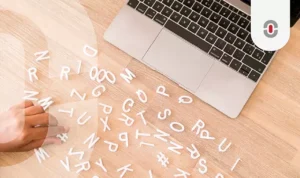 Person arranging scattered 3D letters on a wooden desk next to a laptop, symbolizing AI’s process of language learning and translation.