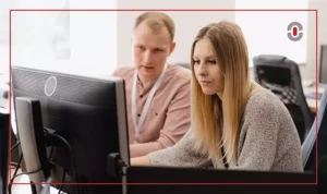 Two colleagues collaborating at a desktop computer, representing the human expertise often required to refine AI-generated translations in localization workflows.