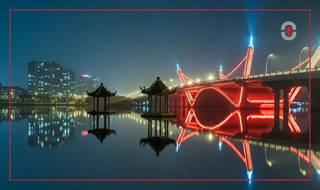 A modern neon-lit bridge beside traditional Chinese pavilions, representing the fusion of innovation and heritage—mirroring how AI blends technology with cultural sensitivity in transcreation.