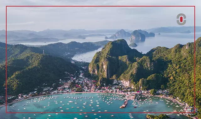 A scenic aerial view of a coastal town in the Philippines surrounded by green mountains and island-dotted waters—symbolizing the country’s regional and linguistic diversity.