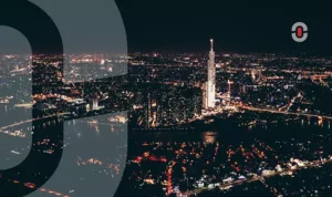 Aerial night view of Ho Chi Minh City, Vietnam, with Landmark 81 tower illuminated and the city skyline reflecting in the river, symbolizing Vietnam’s rapid urban and economic growth.