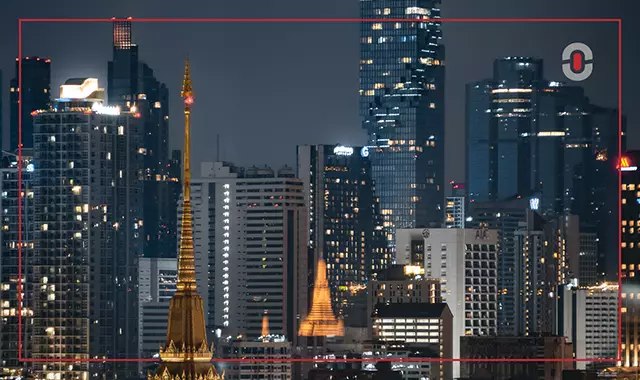 Bangkok skyline at night with illuminated temples and modern skyscrapers, representing the blend of tradition and modernity in Thai culture.