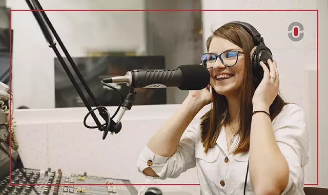 Smiling woman recording voiceover in a studio with headphones and a professional microphone. Represents the human touch still vital in voice work despite AI advances.