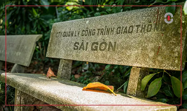 Weathered concrete bench in a lush Vietnamese park with the faded text 'Sài Gòn' written in Quốc Ngữ, Vietnam's modern writing system. Highlights the everyday presence of diacritics in Vietnamese public life and why accurate localization requires cultural familiarity.